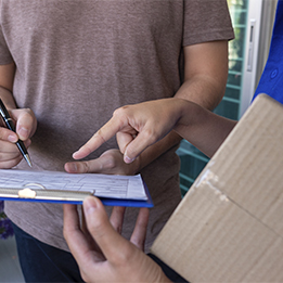 Un homme signe un document, tandis qu'une autre personne porte un carton, illustrant le suivi complet lors d'un déménagement.