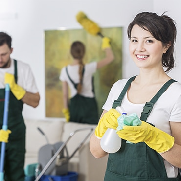 Une équipe de ménage composée de trois personnes en tenue professionnelle, équipées de produits et matériels de nettoyage.