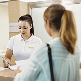Interaction entre un client et une employée à un comptoir, dans un environnement accueillant et professionnel.