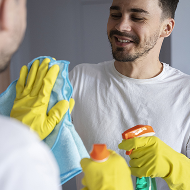 Un homme nettoie un miroir avec des équipements et produits professionnels.