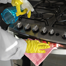 Une personne nettoie une plaque avec des produits de nettoyage, des équipements et des gants.